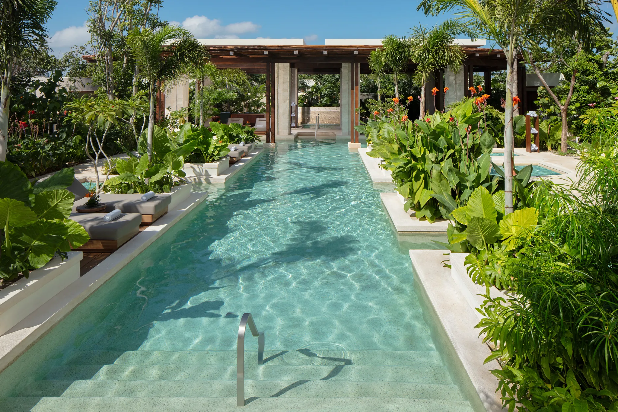 Outdoor hydrotherapy pool surrounded by lush tropical plants at Secrets Playa Blanca Costa Mujeres spa.