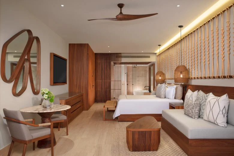 Junior Suite with king bed, sofa seating, and tropical décor at Secrets Playa Blanca Costa Mujeres.