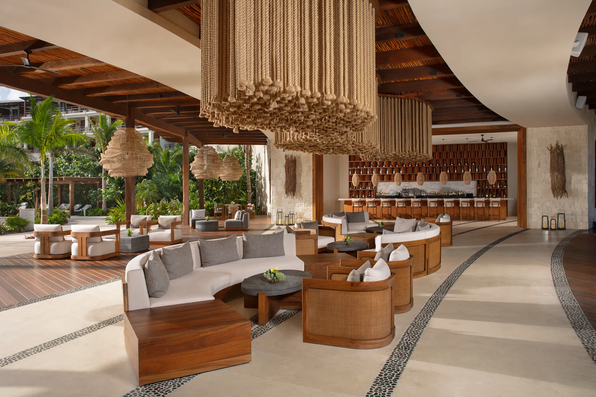 Open-air lounge with modern seating and bar area at Secrets Playa Blanca Costa Mujeres surrounded by tropical greenery.