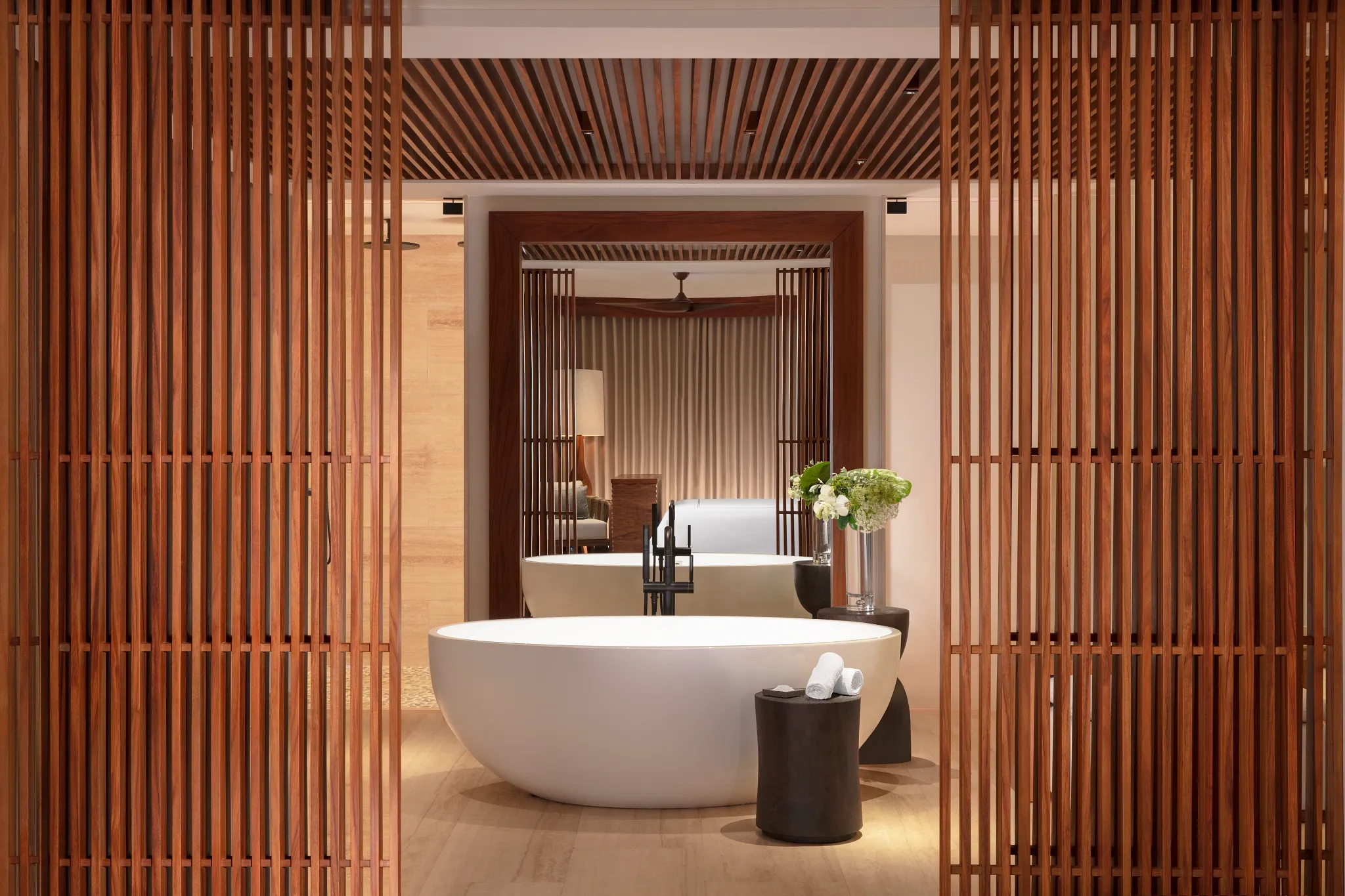 Freestanding soaking tub framed by wood accents in Presidential Suite Ocean Front.